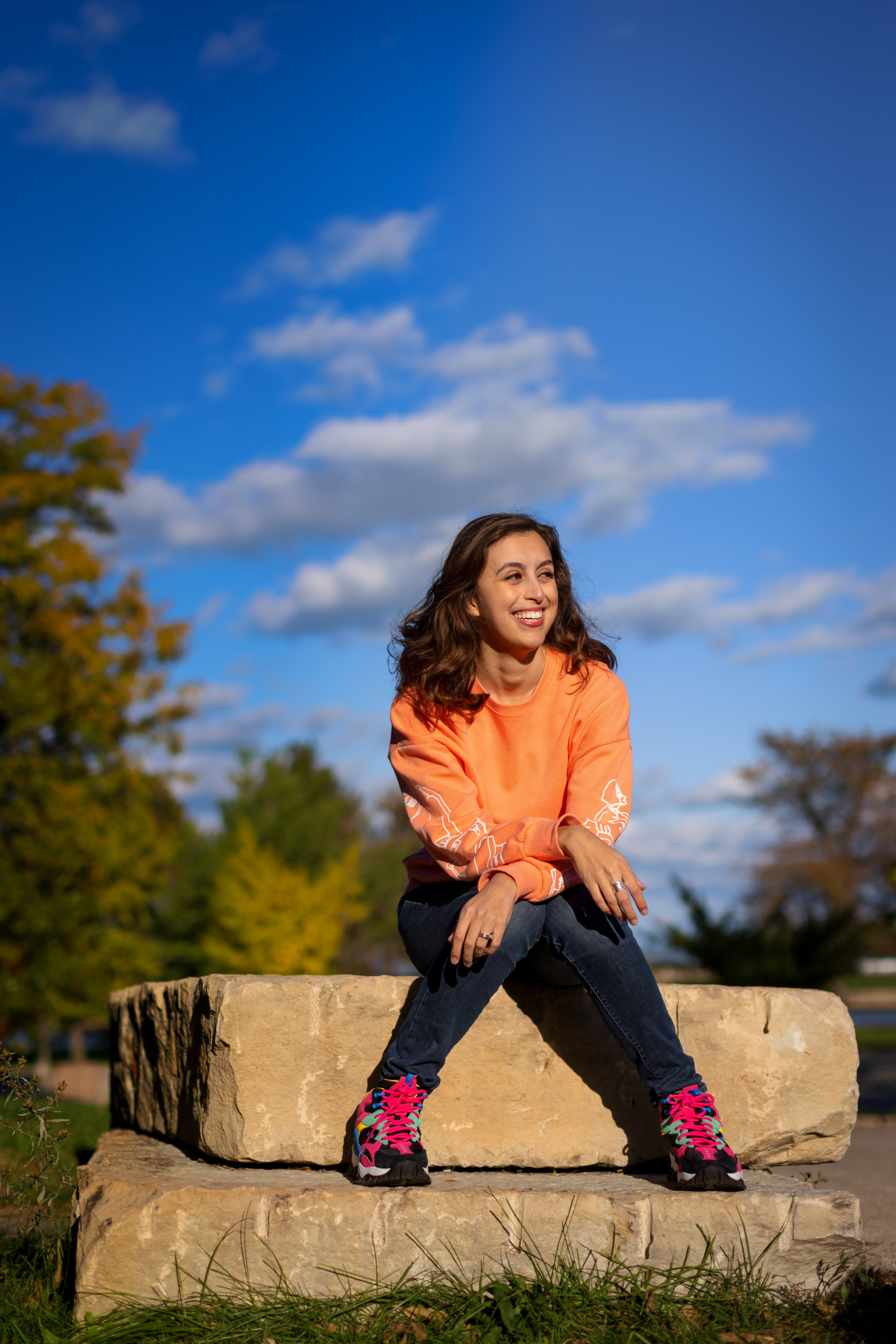 Author Cassidy sitting under blue skies on a rock outside