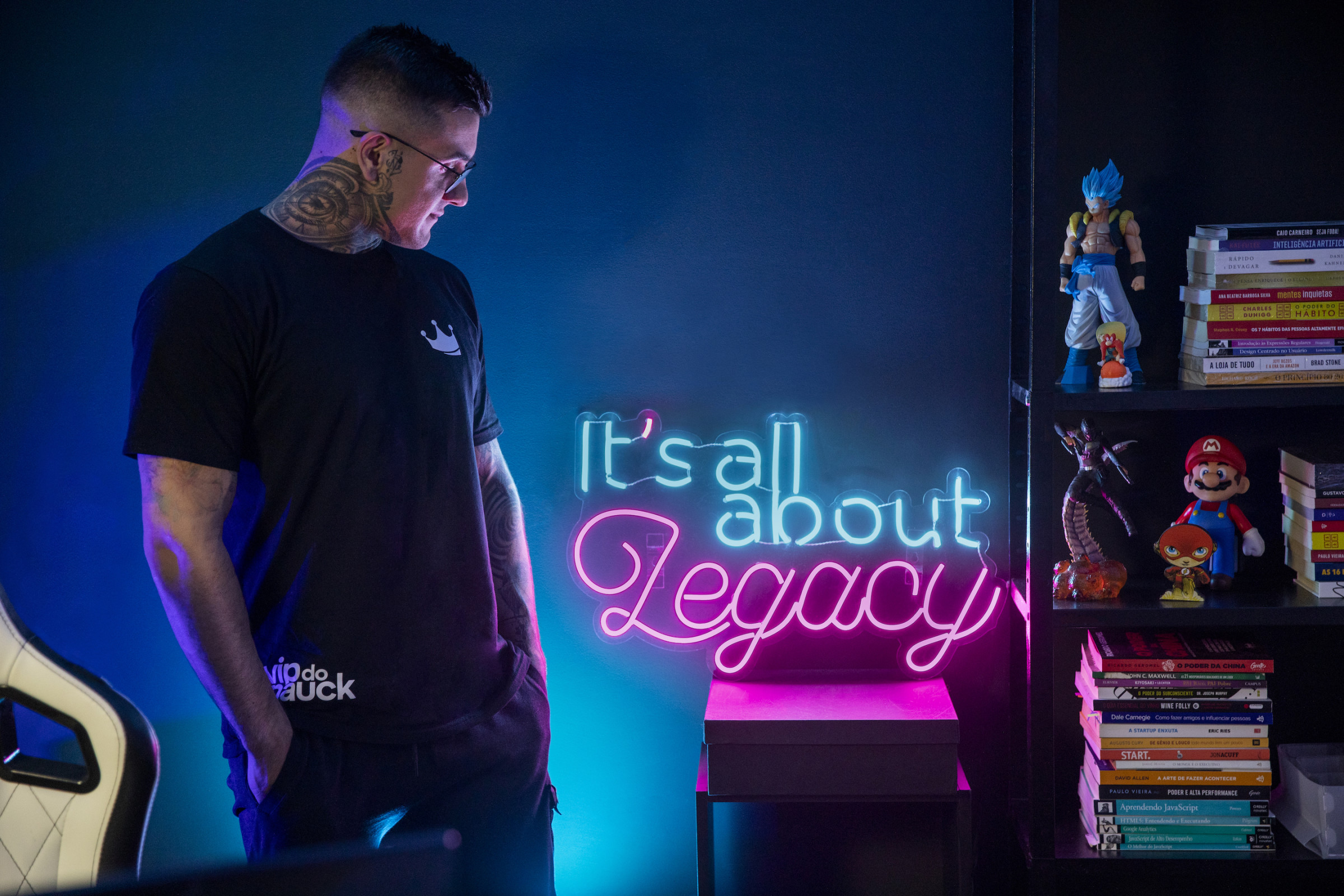 Author Pedro gazing at a blue-and-pink neon sign that says "It's all about legacy"