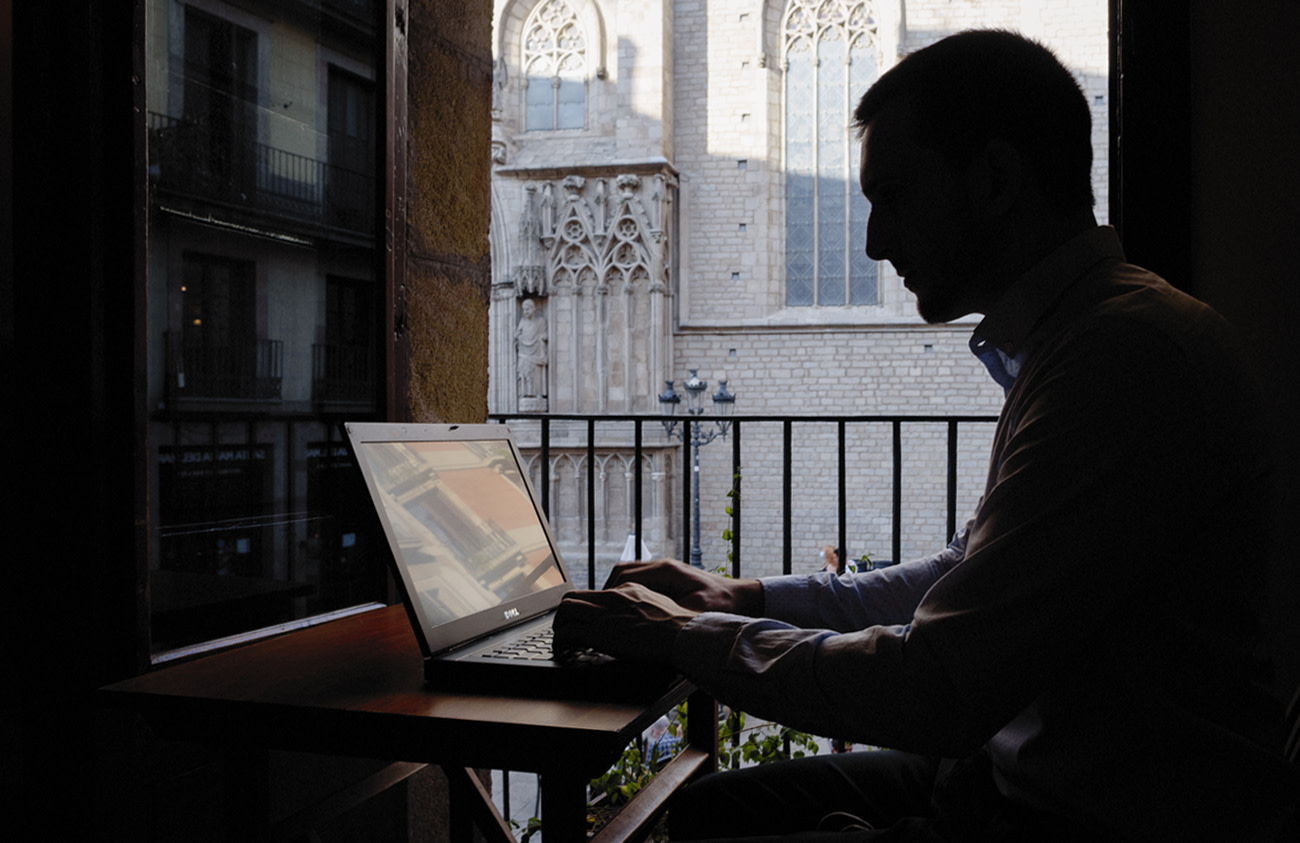 Silhouette of Marc Cornellà working in front of an open window.