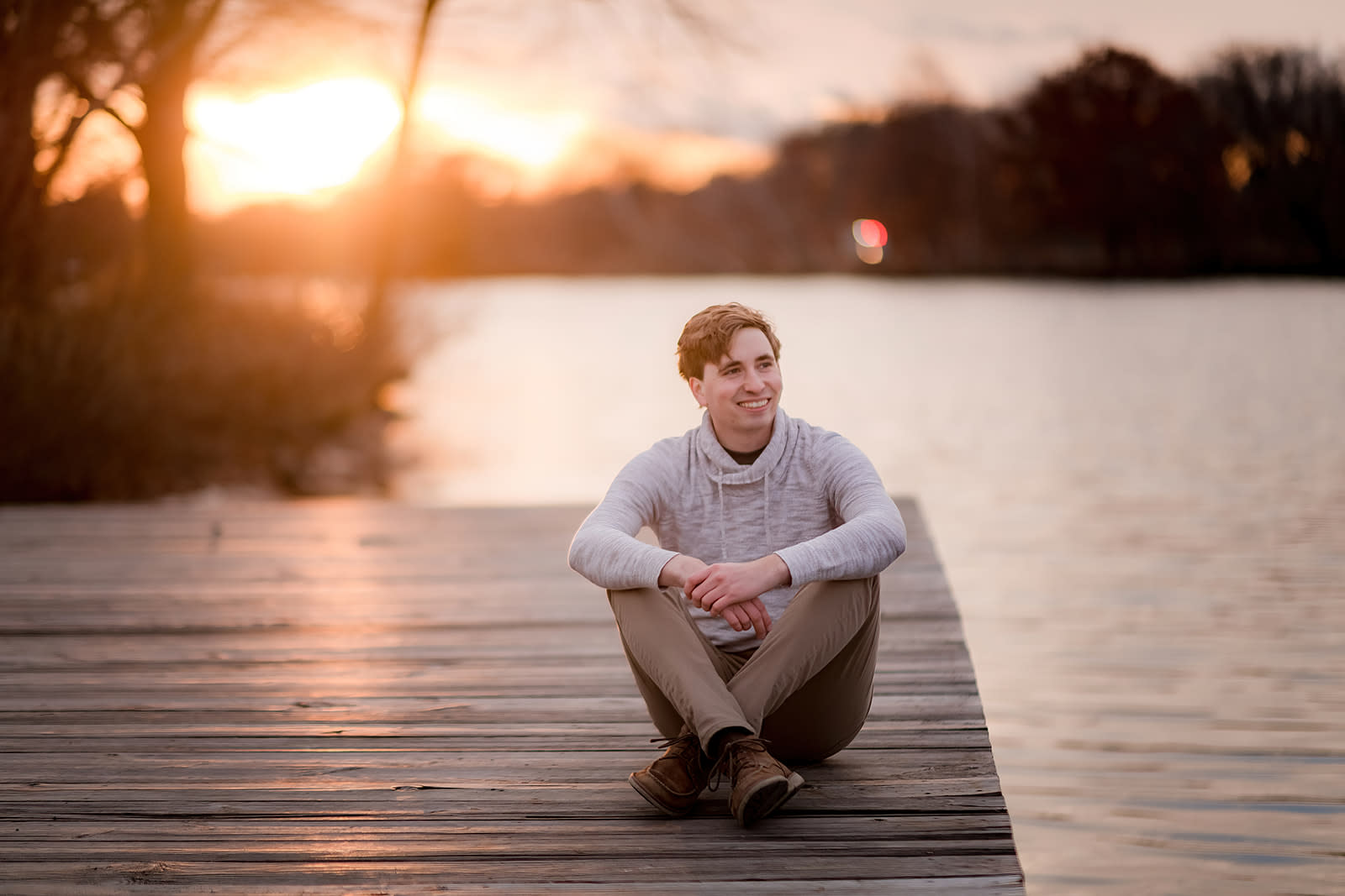Author Jonathan sitting on a dock while the sun sets behind him