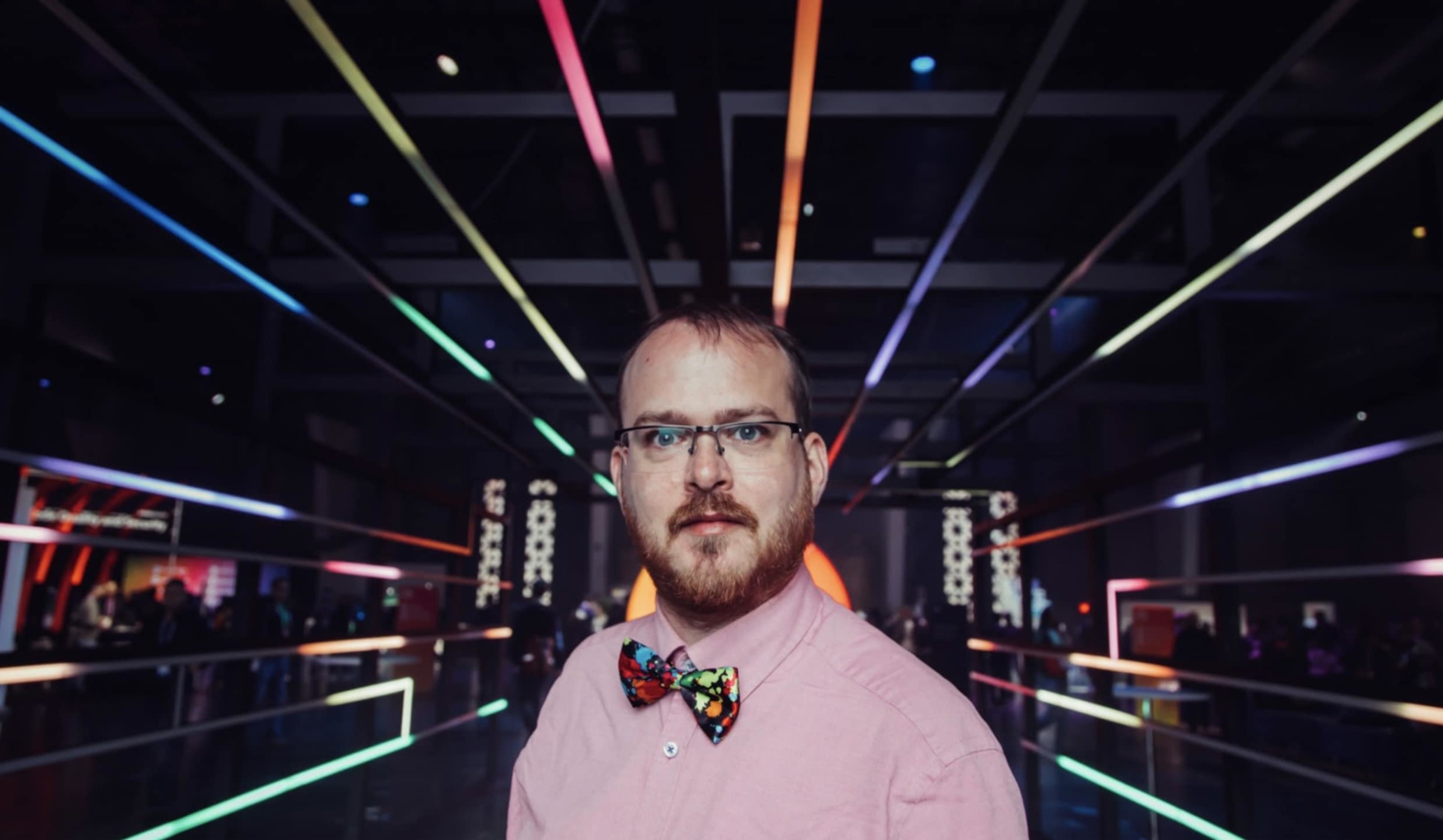 Photo of Dirk Lemstra wearing a colorful bowtie, surrounded by colorful lighted leading lines.