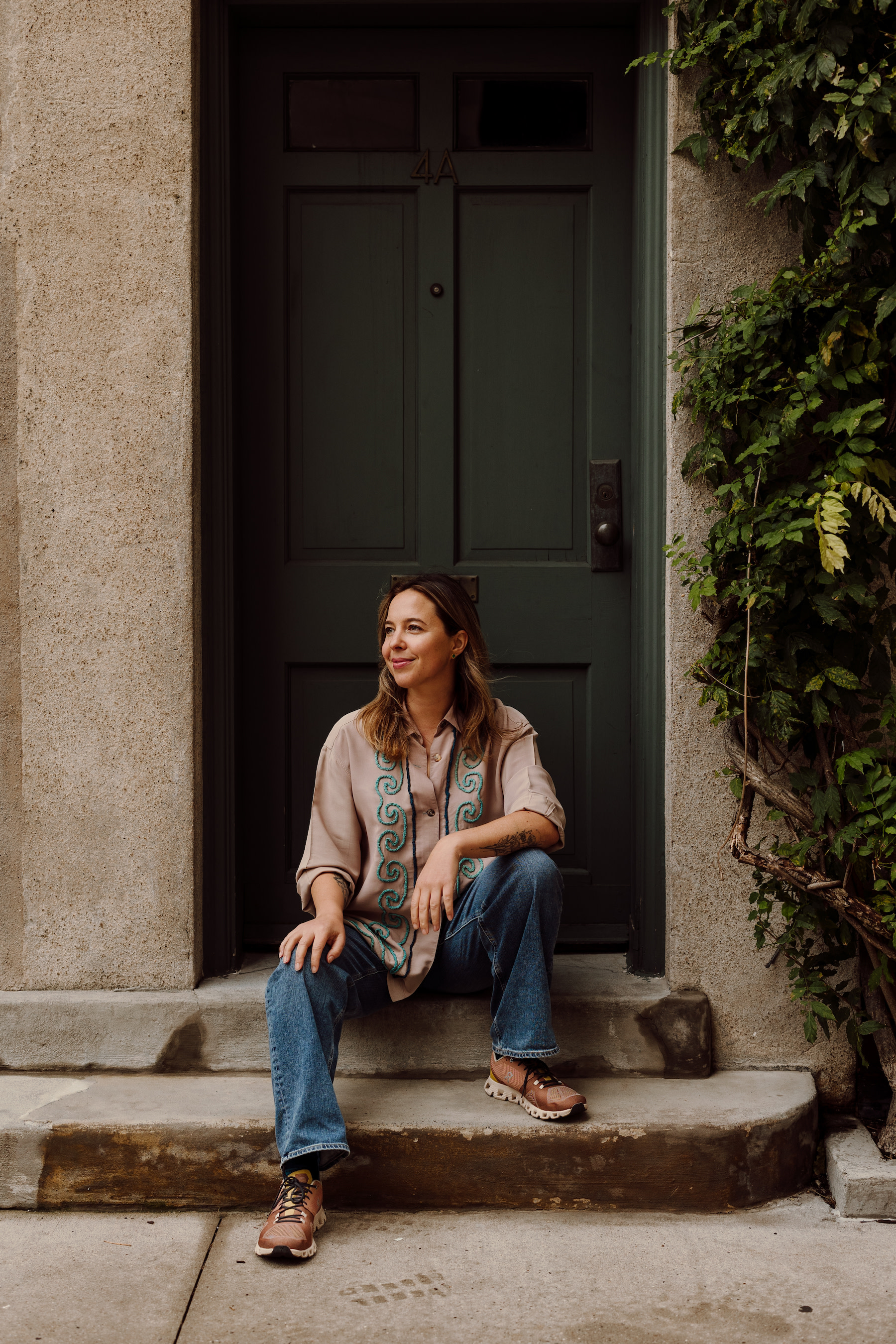 Author Jana sitting and smiling in front of doorstep in a courtyard