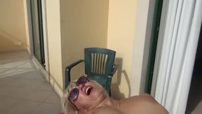 Blonde is masturbating on the balcony at the hotel.